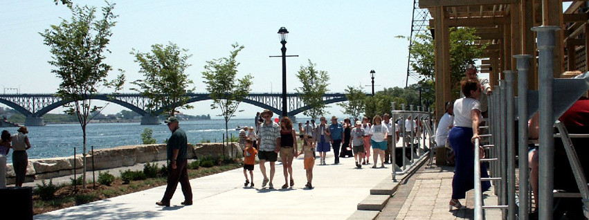 People walkin along the waterfront of the Niagara River with the Peace Bridge in the background